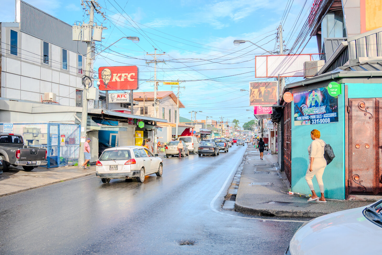 Tunapuna Main Road on the western stretch, with KFC, market stalls, and pedestrians on a typical day.